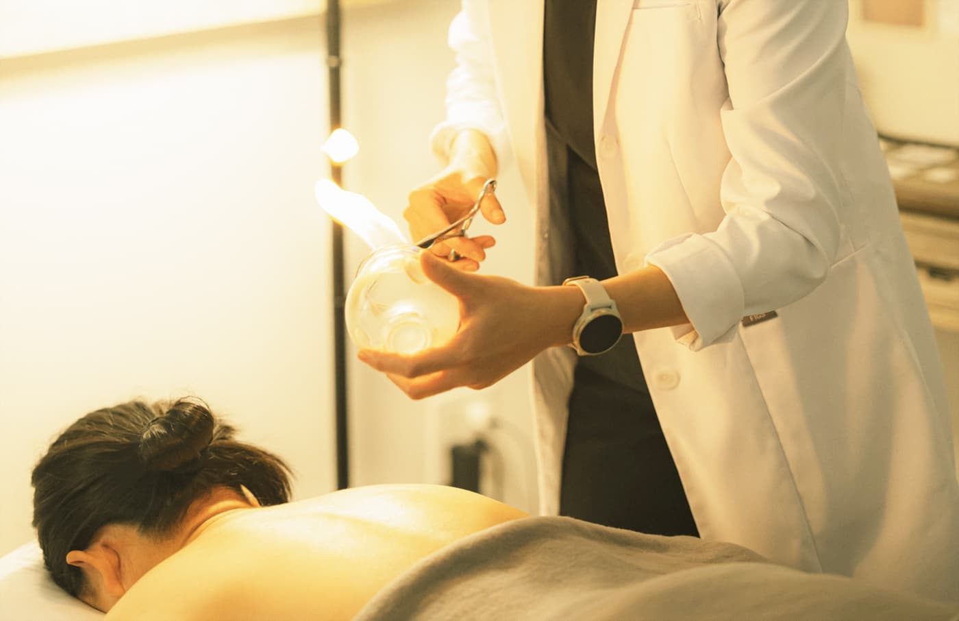 Practitioner smiling while applying a glass cup during treatment